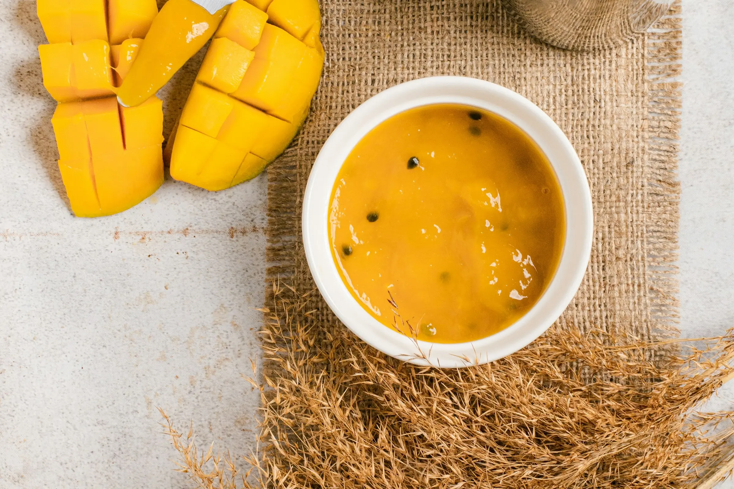 Mango purée in a bowl next to a cut mango