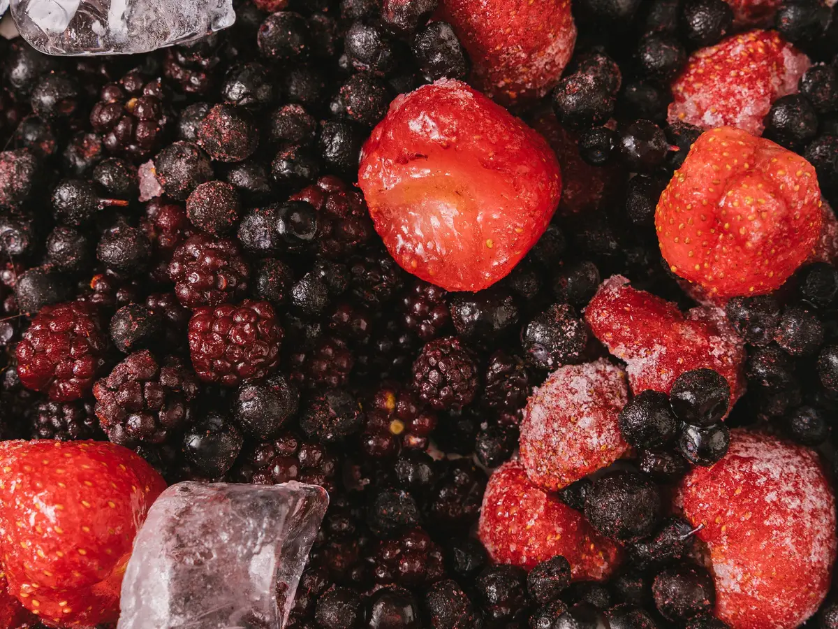 Frozen strawberries on frozen blackberries and blueberries, with ice